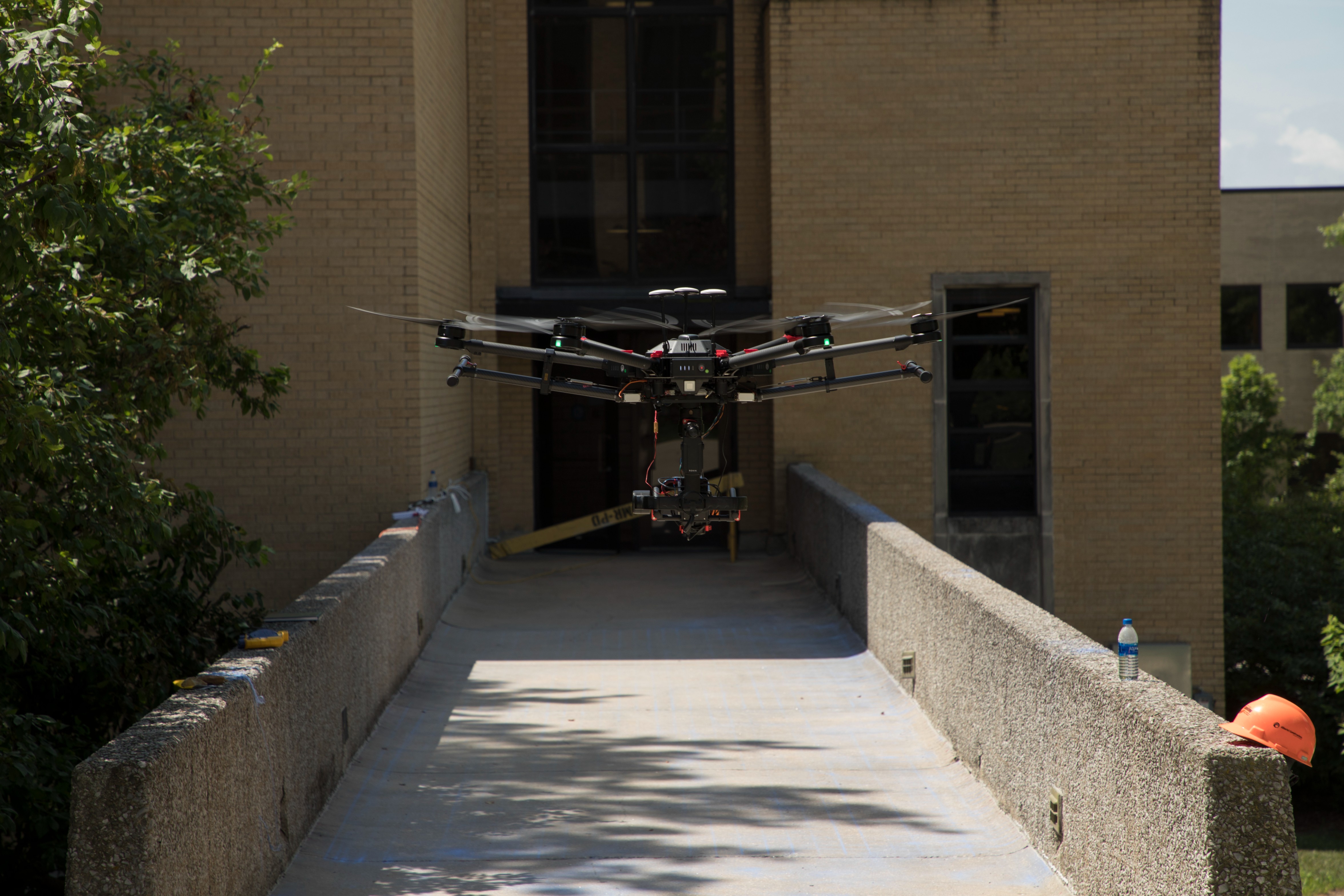 A large drone hovers over a concrete walkway